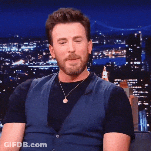 A Man With A Beard Wearing A Blue Vest And Black Shirt GIF