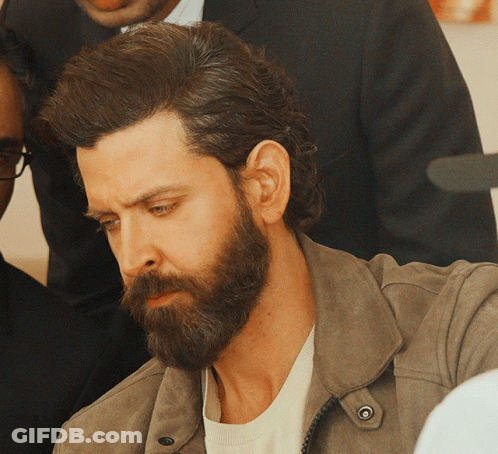 A Man With A Beard Wearing A Brown Jacket GIF