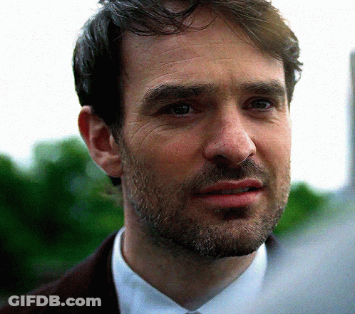 A Man With A Beard Wearing A Brown Jacket And White Shirt GIF