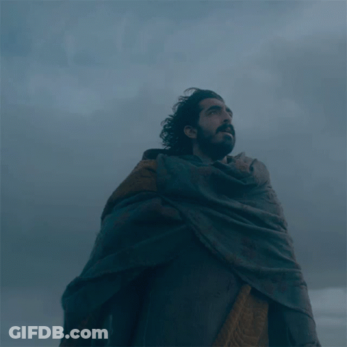A Man With A Beard Wearing A Cape Looks Up Into The Sky GIF