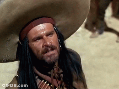 A Man With A Beard Wearing A Cowboy Hat And A Necklace Of Bullets GIF