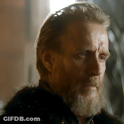 A Man With A Beard Wearing A Fur Coat Looks At The Camera GIF