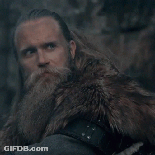 A Man With A Beard Wearing A Fur Coat Looks At The Camera GIF