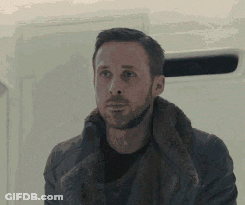 A Man With A Beard Wearing A Fur Coat Looks At The Camera GIF