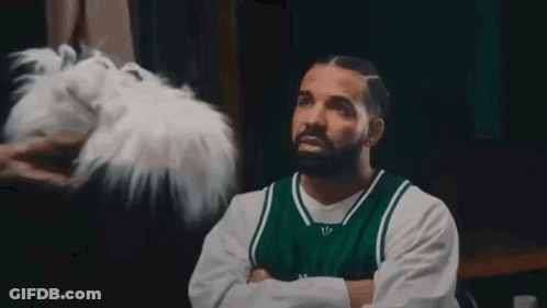 A Man With A Beard Wearing A Green And White Jersey Has Question Marks Around His Head . GIF