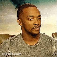 Bearded Man In Grey Shirt Sitting And Looking At Camera GIF