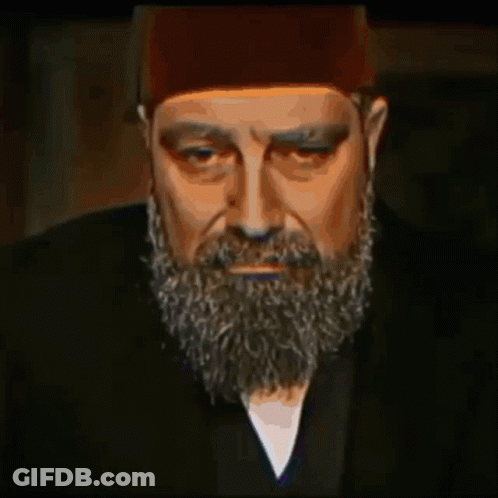 A Man With A Beard Wearing A Hat And A Black Jacket GIF