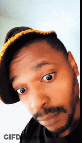 A Man With A Beard Wearing A Hat And A Black Shirt GIF