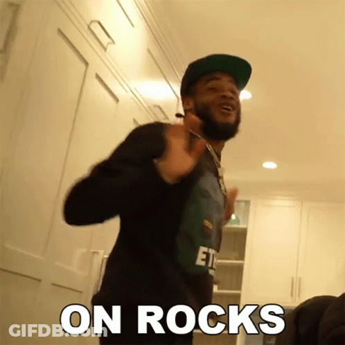 A Man With A Beard Wearing A Hat And A Shirt That Says " On Rocks " On It GIF