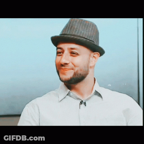 A Man With A Beard Wearing A Hat And A Striped Shirt GIF
