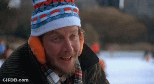 A Man With A Beard Wearing A Hat And Ear Muffs Is Sitting On A Ice Rink . GIF