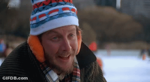 A Man With A Beard Wearing A Hat And Ear Muffs Is Smiling . GIF