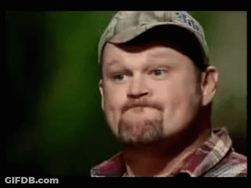 A Man With A Beard Wearing A Hat And Plaid Shirt Is Making A Funny Face . GIF