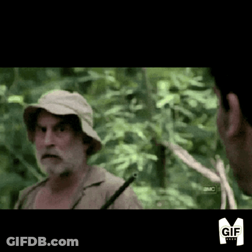 A Man With A Beard Wearing A Hat Is Talking To Another Man In The Woods GIF