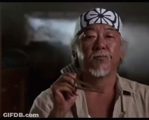 A Man With A Beard Wearing A Headband Is Holding A Pair Of Scissors . GIF