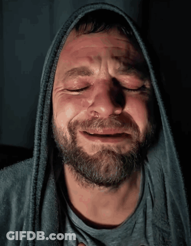 A Man With A Beard Wearing A Hooded Sweatshirt Is Crying With His Eyes Closed GIF