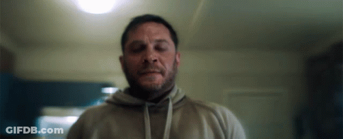A Man With A Beard Wearing A Hoodie Is Standing In A Room . GIF