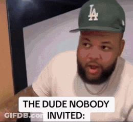 A Man With A Beard Wearing A La Hat Is Sitting In Front Of A Computer . GIF