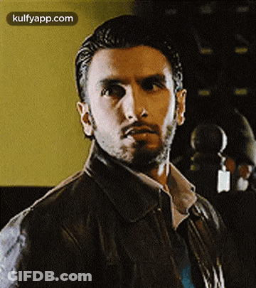 A Man With A Beard Wearing A Leather Jacket And Tie Is Looking At The Camera . GIF