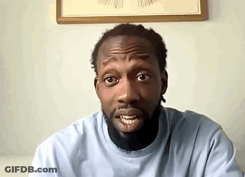 A Man With A Beard Wearing A Light Blue Shirt Looks At The Camera GIF