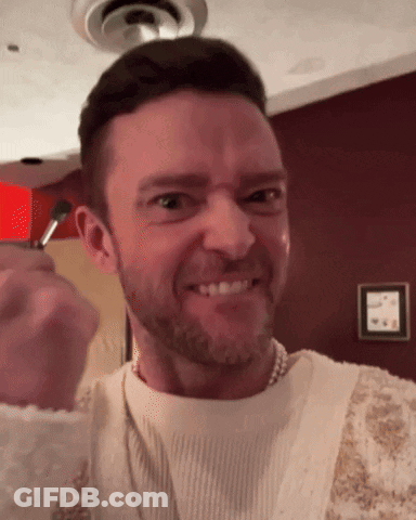 A Man With A Beard Wearing A Pearl Necklace Is Making A Funny Face GIF