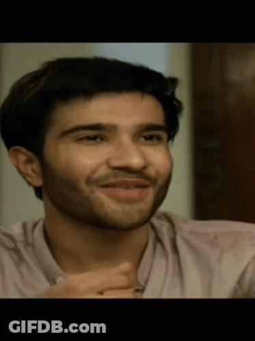 A Man With A Beard Wearing A Pink Shirt Is Smiling GIF