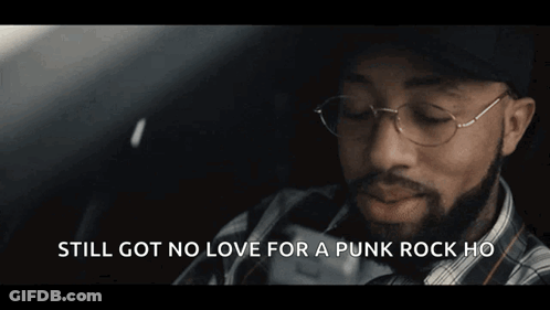 A Man With A Beard Wearing A Plaid Shirt And A Baseball Cap Says " Still Got No Love For A Punk Rock Ho " GIF