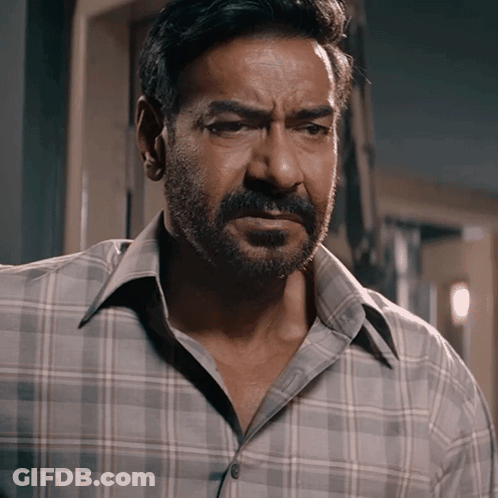 A Man With A Beard Wearing A Plaid Shirt Is Looking At The Camera GIF