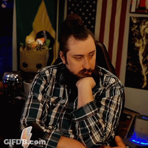 A Man With A Beard Wearing A Plaid Shirt Is Sitting In A Chair With His Head Resting On His Hand . GIF