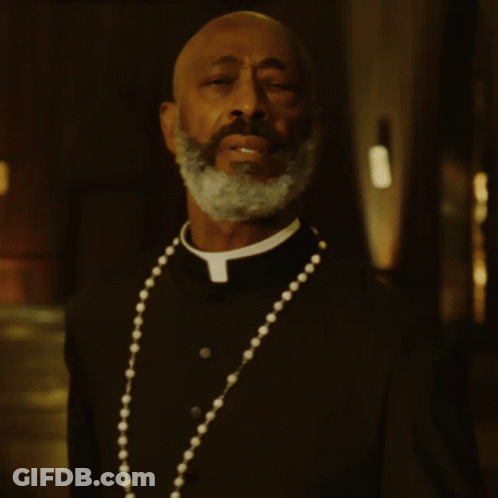 A Man With A Beard Wearing A Priest Collar And A Necklace GIF