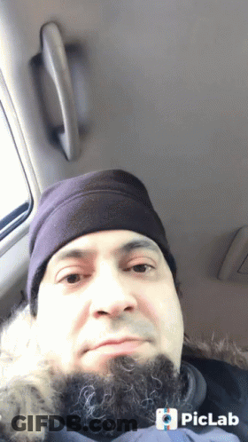 A Man With A Beard Wearing A Purple Hat Is Sitting In The Back Seat Of A Vehicle GIF