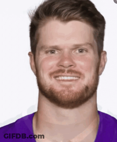 A Man With A Beard Wearing A Purple Shirt Is Smiling GIF
