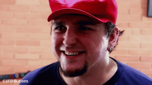 A Man With A Beard Wearing A Red Hat And Smiling GIF