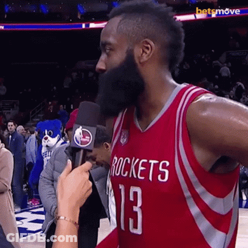 A Man With A Beard Wearing A Rockets Jersey Is Being Interviewed By A Reporter GIF