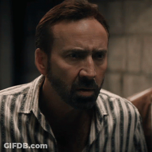 A Man With A Beard Wearing A Striped Shirt Is Looking At The Camera GIF