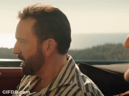 A Man With A Beard Wearing A Striped Shirt Is Sitting In The Back Seat Of A Car GIF