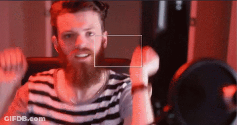 A Man With A Beard Wearing A Striped Shirt Is Smiling GIF