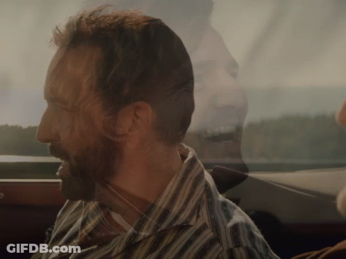 A Man With A Beard Wearing A Striped Shirt Looks Out The Window GIF