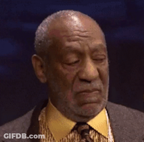A Man With A Beard Wearing A Suit And Tie Is Making A Funny Face . GIF
