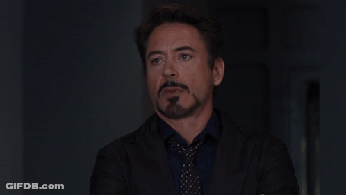 A Man With A Beard Wearing A Suit And Tie Looks At The Camera GIF