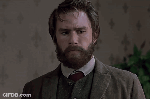 A Man With A Beard Wearing A Suit And Tie Looks At The Camera GIF