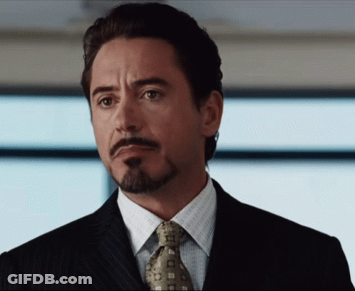 A Man With A Beard Wearing A Suit And Tie Looks To The Side GIF