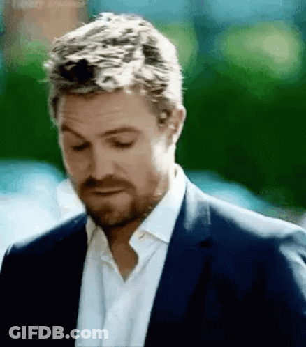 A Man With A Beard Wearing A Suit And White Shirt Is Looking Down . GIF