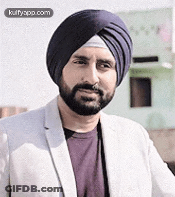 A Man With A Beard Wearing A Turban And A White Jacket Is Smiling . GIF