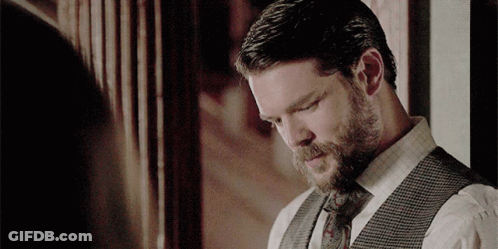 A Man With A Beard Wearing A Vest And Tie Is Looking Down GIF