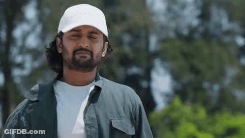 A Man With A Beard Wearing A White Hat And A Gray Shirt . GIF