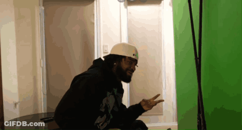 A Man With A Beard Wearing A White Helmet And A Black Hoodie GIF