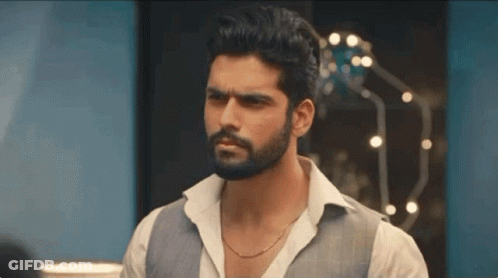 A Man With A Beard Wearing A White Shirt And A Gray Vest Is Standing In A Room . GIF