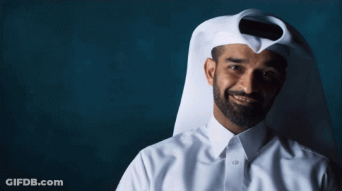 A Man With A Beard Wearing A White Shirt And A Scarf Covering His Face GIF
