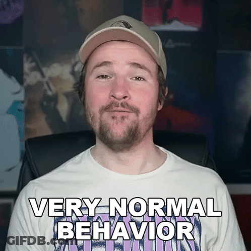 A Man With A Beard Wearing A White Shirt That Says Very Normal Behavior GIF